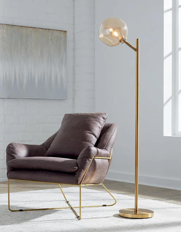 Grey leather lounge chair with a brass globe floor lamp