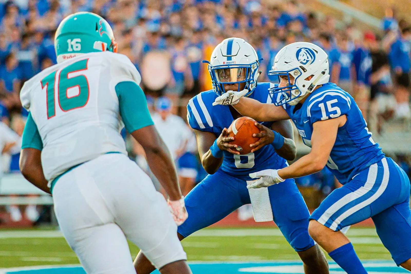 Quarterback handing off during a night football game
